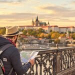 Tourist with map overlooking Prague cityscape at sunset