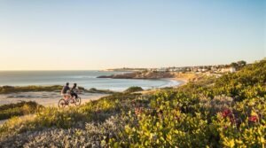 Couple cycling along a coastal path near a beach.